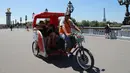 Wisatawan berkeliling kota Paris menggunakan transportasi becak, Prancis, (7/7). Desain becak di Paris ini memiliki posisi penarik becak dibagian depan berbeda dengan becak yang ada di Indonesia. (AFP Photo/Jacques Demarthon)