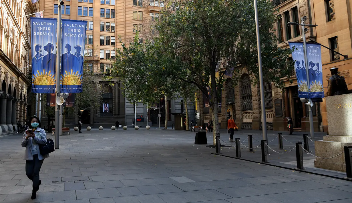 Seorang perempuan mengenakan masker berjalan melalui Martin Place yang tenang di kawasan pusat bisnis di Sydney saat lockdown minggu kedua untuk meredam gejolak varian Delta Covid-19, Selasa (6/7/2021). Nasib lockdown di Sydney akan ditentukan dalam 24 jam ke depan. (Bianca De Marchi/AFP)