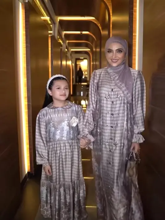 Ashanty tampil kembaran dengan sang buah hati mengenakan dress satin full motif yang elegan. Ia melengkapi gayanya dengan scarf warna senada [@ashanty_ash]