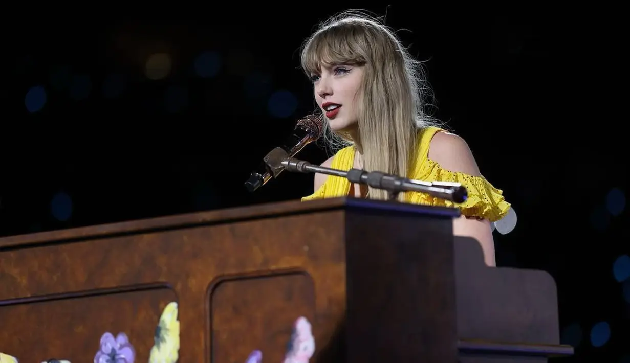 Melihat lebih dekat kecantikan Taylor Swift. Mengenakan gaun berwarna kuning dan sedang bermain piano, Taylor Swift terlihat dengan wajah cantiknya, rambut berponi yang dibiarkan tergerai, winged-eyeliner, dan lipstik merah merona. [Foto: Instagram/taylorswift]