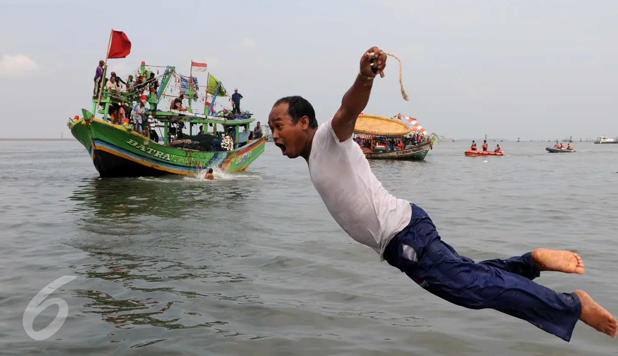 Seorang nelayan menceburkan diri ke laut saat mengikuti sedekah bumi Nadran di Muara Angke, Jakarta, Minggu (13/12). Tradisi ini sebagai ungkapan rasa syukur kepada Tuhan YME atas hasil laut yang diperoleh. (Liputan6.com/Helmi Afandi)