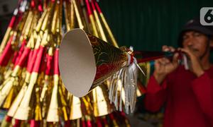 Pedagang sedang menjajal terompet buatannya di kawasan Glodok, Jakarta, Selasa (26/12/2023). (Liputan6.com/Faizal Fanani)