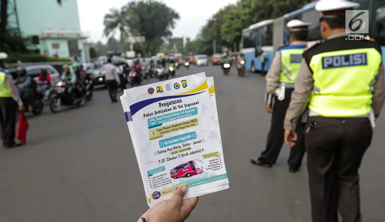 Petugas Dinas Perhubungan menunjukkan selebaran sosialisasi pemberlakuan sistem ganjil genap di pintu masuk Gardu Tol Cibubur 2, Jakarta, Senin (16/4). Aturan ini berlaku untuk kendaraan pribadi atau golongan I dan II. (Liputan6.com/Faizal Fanani)
