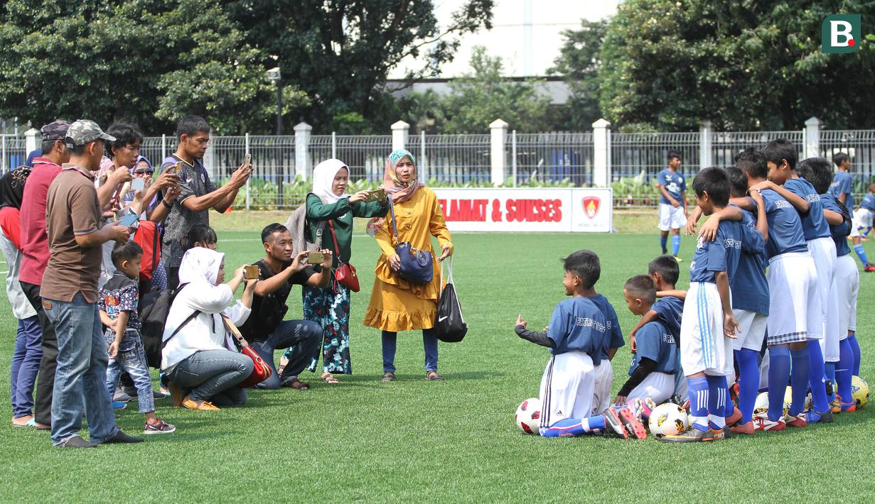 Orang tua mengabadikan momen saat anak-anak mereka mengikuti coaching clinic di Lapangan ABC Senayan, Jakarta, Rabu (28/3/2018). Acara ini dalam rangkaian peluncuran Patriot 165 FC. (Bola.com/Asprilla Dwi Adha)