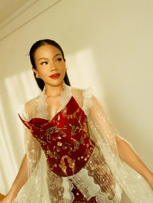 Belahan tinggi pada rok memamerkan siluet anggun, sementara sandal heels berwarna emas melengkapi penampilan penuh percaya diri. Riasan wajah bernuansa bold dengan lipstik merah dan tatanan rambut sleek mempertegas aura elegan nan modern. [@yurayunita].