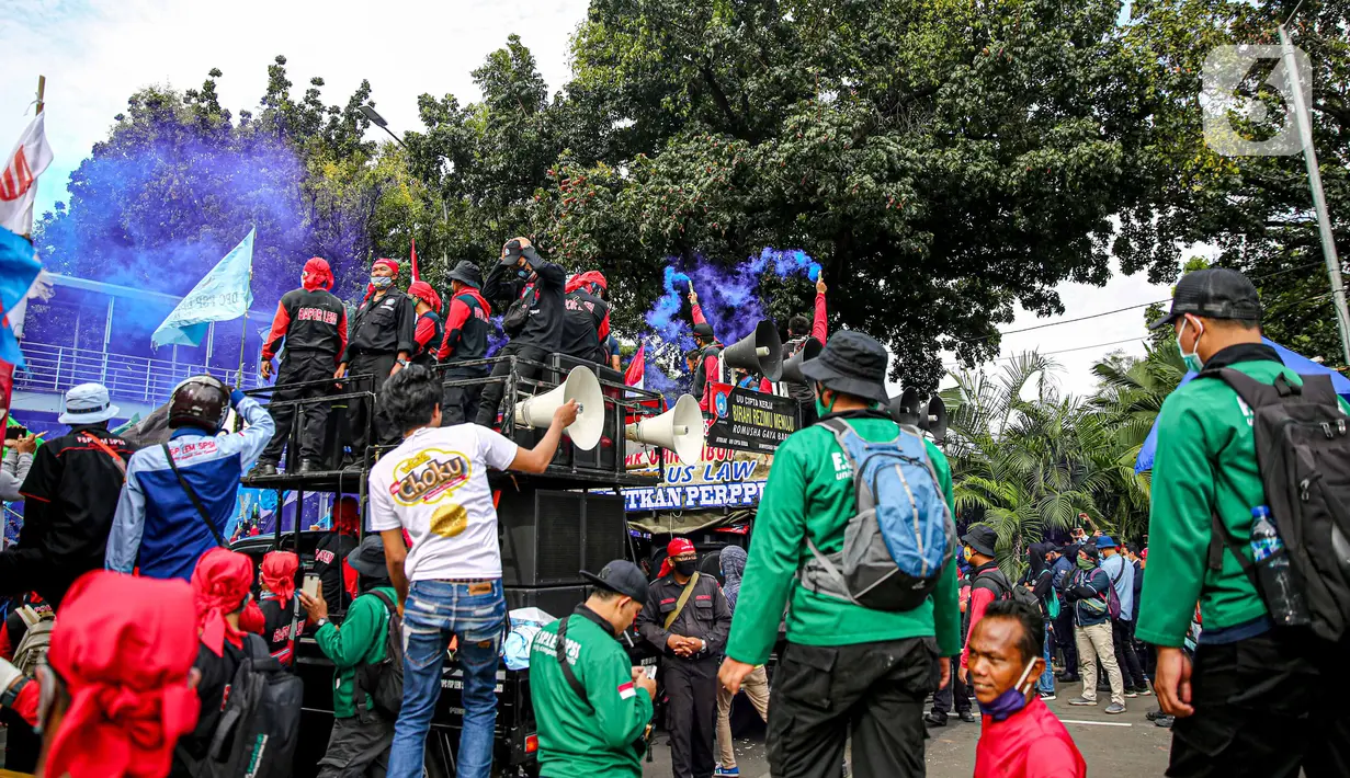 Massa buruh menyalakan asap suar saat unjuk rasa di Patung Kuda, Jakarta, Kamis (22/10/2020). Aksi gabungan buruh, petani, mahasiswa, dan pelajar dilakukan untuk menyuarakan penolakan pengesahan UU Cipta Kerja dan meminta Presiden mengeluarkan Perppu. (Liputan6.com/Faizal Fanani)