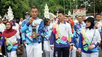 Salah seorang atlet para atletik sedang membawa lentera didampingi Ketua Inapgoc, Raja Sapta Oktahari.(Liputan6.com/Fajar Abrori)