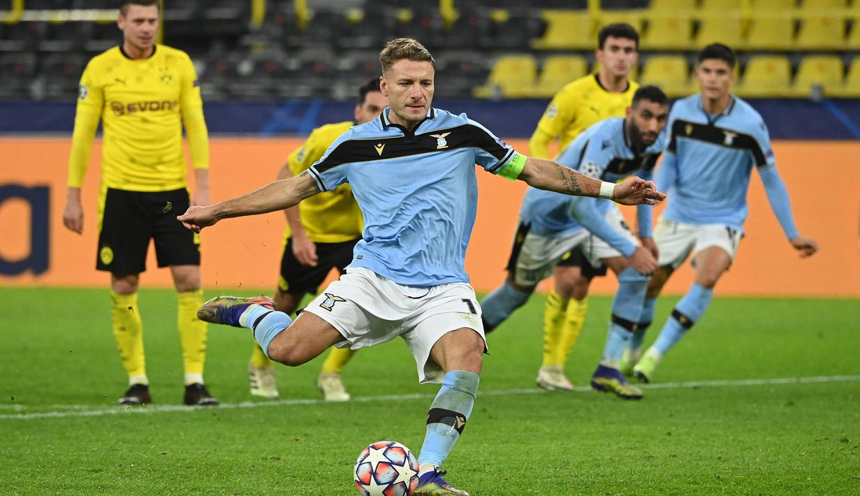 Striker Lazio, Ciro Immobile, melakukan eksekusi penalti ke gawang Borussi Dortmund dalam laga lanjutan Liga Champions 2020/21 Grup F di Signal Iduna Park Stadium, Dortmund, Rabu (2/12/2020) waktu setempat. Lazio bermain imbang 1-1 dengan Dortmund. (AFP/Ina Fassbender)