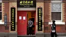 Seorang perempuan berjalan melewati sebuah restoran di jalan yang sepi ketika yang lain menunggu pesanan takeaway di Chinatown Melbourne ketika kota itu bersiap untuk mencabut beberapa pembatasan pada akhir pekan ini setelah mengalami lockdown keenam, Selasa (19/10/2021). (William WEST/AFP)