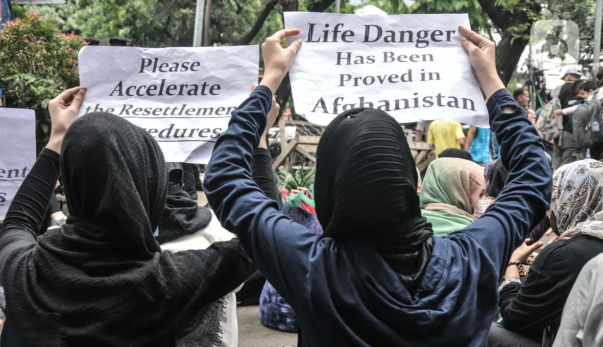 Pencari suaka asal Afghanistan membawa poster tuntutan di depan Kantor UNHCR, Jakarta, Senin (15/11/2021).  Ratusan pencari suaka tersebut menuntut segera dipindahkan ke negara ketiga yang terbebas dari konflik perang setelah lebih 10 tahun mengungsi di Indonesia. (merdeka.com/Iqbal S Nugroho)