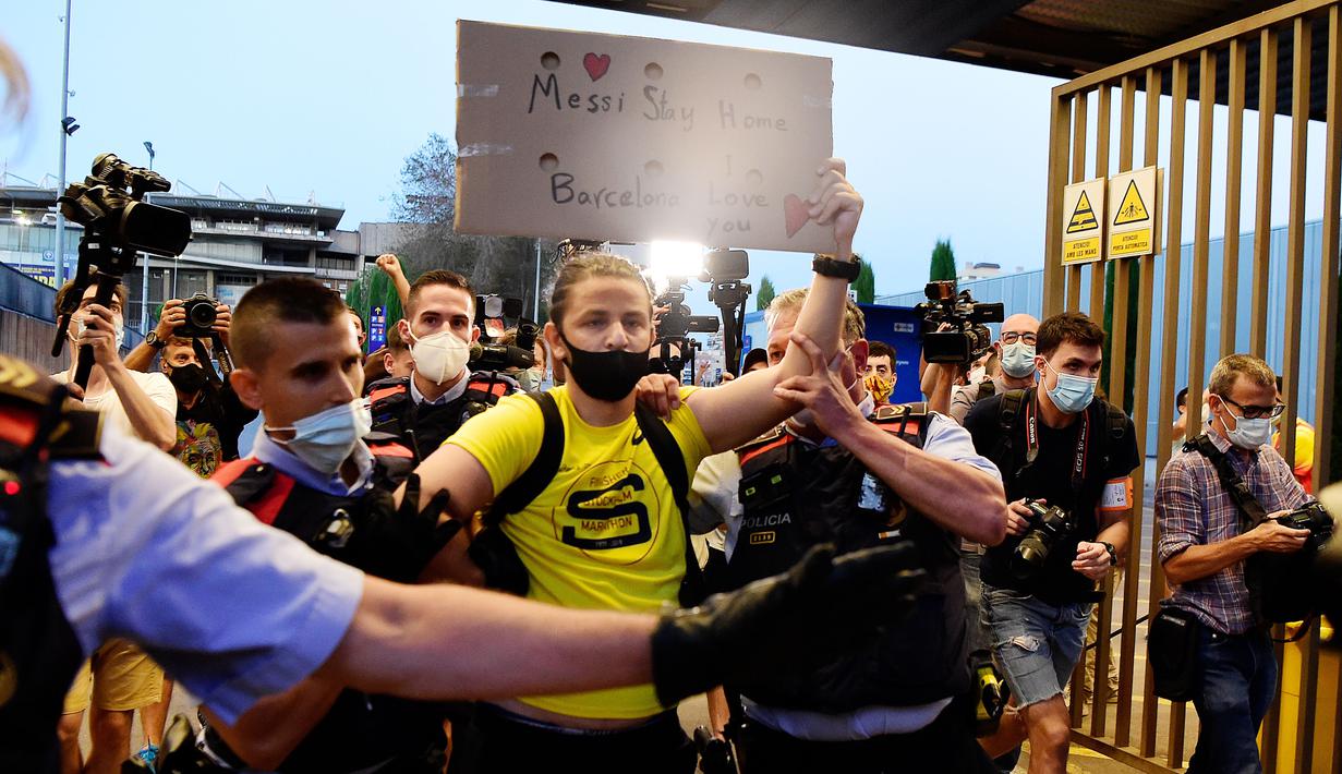 Suporter dikawal petugas keamanan saat protes di depan kantor Barcelona, Rabu (26/8/2020). Dalam aksi tersebut fans meminta Lionel Messi bertahan dan menuntut Josep Maria Bartomeu mundur dari jabatannya. (AFP/Pau Barrena)