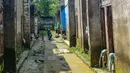 Warga memperbaiki sepedanya dengan deretan rumah yang ditinggal pemiliknya akibat kerapkali banjir karena luapan Pesanggrahan yang alirannya menyempit karena longsoran sampah dari Tempat Pembuangan Akhir (TPA) Cipayung di Perumahan Griya Alif, Sawangan, Depok, Jawa Barat, Kamis (14/5/2026). (merdeka.com/Arie Basuki)