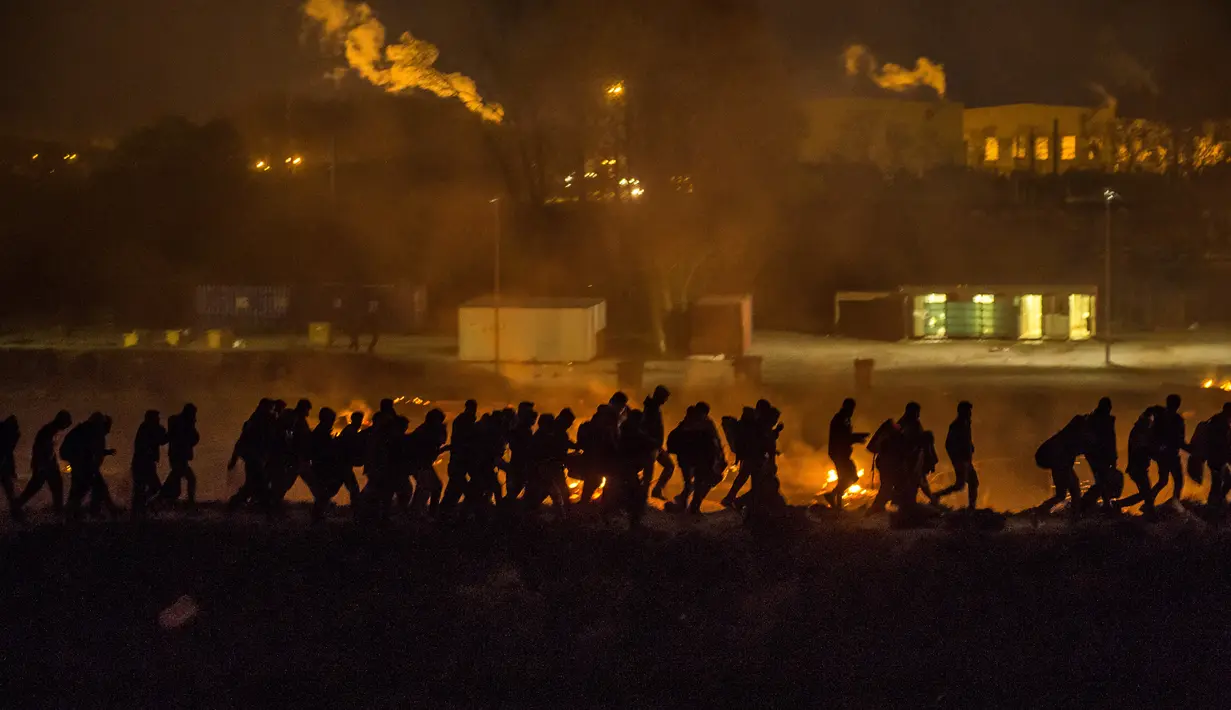 Imigran meninggalkan kamp penampungan mereka yang terbakar di Dunkirk, Prancis, Senin (10/4).  Di kamp penampungan ini setidaknya telah tinggal sebanyak 1500 imigran. (AFP PHOTO / PHILIPPE HUGUEN)