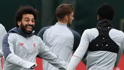 Gelandang Liverpool Mohamed Salah (kiri) bercanda dengan rekan setimnya saat sesi latihan jelang menghadapi Bayern Munchen dalam leg kedua babak 16 besar Liga Champions di Melwood, Liverpool, Inggris, Selasa (12/3). (Paul ELLIS/AFP)