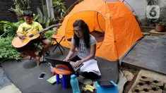 Warga bekerja menggunakan laptop di halaman rumahnya di kawasan Cinere, Depok, Senin (23/3/2020). Imbauan pemerintah untuk bekerja dari rumah atau work from home untuk mencegah penularan virus corona, dimanfaatkan warga dengan beragam aktivitas. (merdeka.com/Arie Basuki)