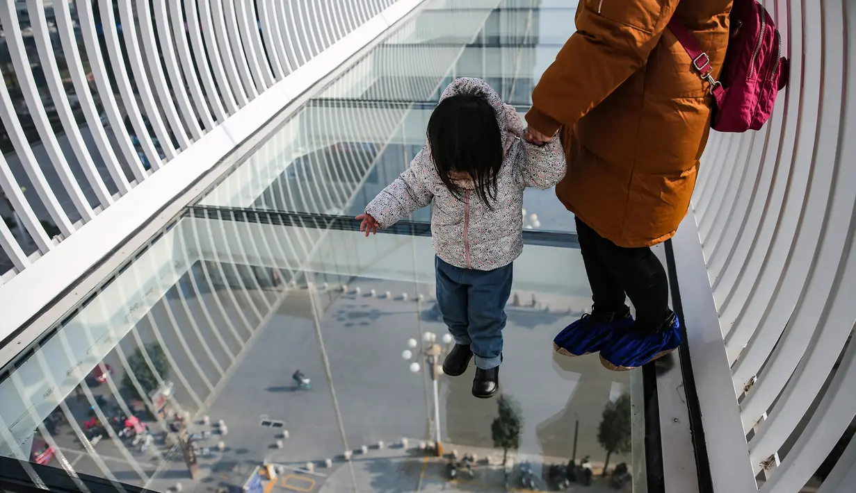 Seorang bocah melintasi jembatan kaca di Shijiazhuang, Provinsi Hebei, China, Sabtu (24/11). (AFP)