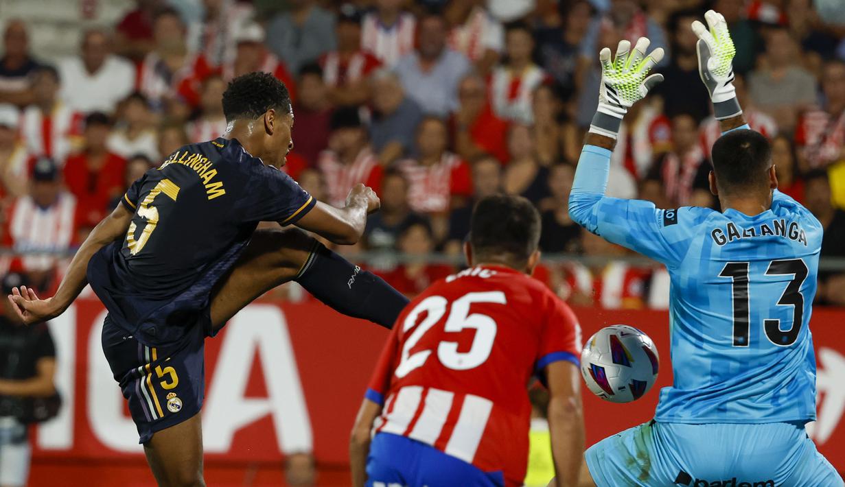 Kiper Girona, Paulo Gazzaniga (kanan) melakukan penyelamatan atas tendangan gelandang Real Madrid, Jude Bellingham (kiri) pada laga pekan ke-8 Liga Spanyol 2023/2024 di Montilivi Stadium, Girona, Spanyol, Sabtu (30/9/2023) malam WIB. (AP Photo/Joan Monfort)
