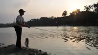 Warga memancing ikan di Danau Setu Babakan di Jagakarsa, Jakarta, Minggu (11/6). Memancing menjadi kegiatan warga sekitar Setu untuk mengisi waktu Ngabuburit. (Liputan6.com/Yoppy Renato)