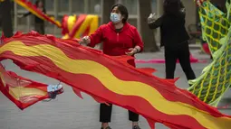 Seorang wanita mengenakan masker mengibarkan bendera di taman umum di Beijing, Kamis (21/4/2022). Di daratan China, jumlah kematian meningkat menjadi lebih dari 20 dalam wabah di Shanghai yang menutup kota terbesar di negara itu. (AP Photo/Mark Schiefelbein)
