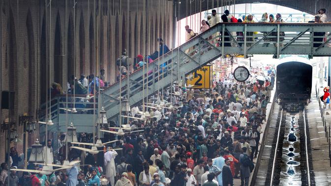 Para pelancong menunggu rangkaian kereta saat mudik menuju kampung halaman untuk merayakan Idul Adha di stasiun Lahore, Pakistan, Sabtu (10/8/2019). Umat Islam di seluruh dunia merayakan Idul Adha yang identik dengan tradisi berkurban. (Photo by ARIF ALI / AFP)