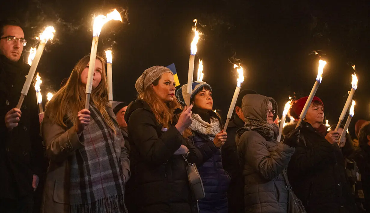 Orang-orang memegang obor saat demonstrasi mendukung Ukraina yang diselenggarakan oleh Greenpeace di Heroes Square, Budapest, Hungaria, 9 Maret 2022. Invasi Rusia ke Ukraina telah memicu migrasi massal terbesar di Eropa dalam beberapa dekade. (AP Photo/Anna Szilagyi)
