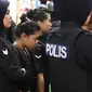 Tersangka kasus pembunuhan Kim Jong-nam, Siti Aisyah dengan kawalan polisi dibawa menuju Bandara Internasional Kuala Lumpur, Selasa (24/10). Siti terlihat mengenakan rompi anti-peluru saat mengunjungi tempat kejadian perkara itu. (AP/Sadiq Asyraf)