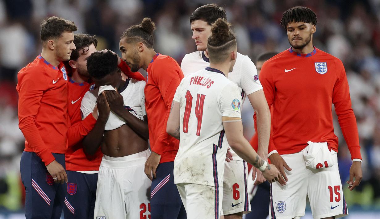 Para pemain Timnas Inggris berusaha menenangkan Bukayo Saka yang gagal mengekusi penalti saat melawan Italia pada laga final Euro 2020 di Stadion Wembley, London, Senin (12/07/2021). (Foto: AP/Carl Recine,Pool)