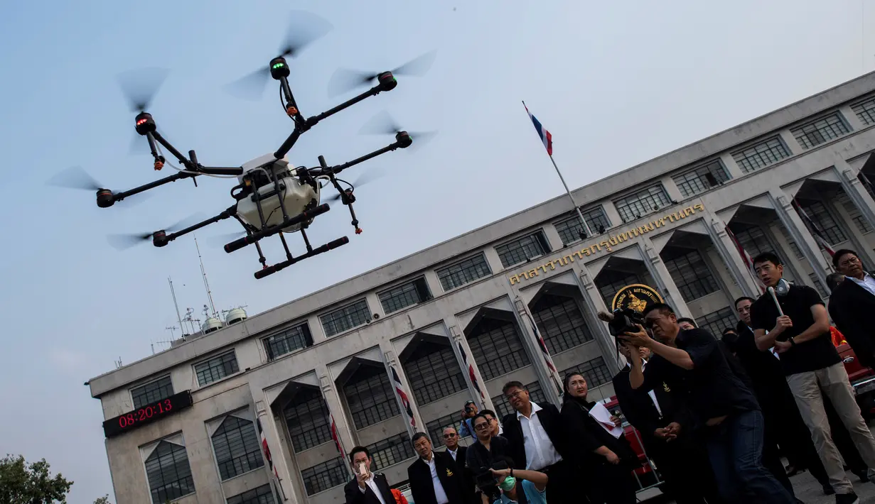 Petugas Administrasi Metropolitan Bangkok (BMA) melihat demonstrasi drone untuk menurunkan hujan buatan, Kamis (31/1). Thailand mengerahkan drone untuk menyemprotkan air dalam membantu memerangi polusi udara di Ibu Kota yang makin parah. (Jewel SAMAD/AFP)