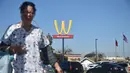 Seorang wanita berjalan dengan latar belakang plang logo restoran cepat saji McDonald's yang terbalik di Lynwood, California (8/3). Huruf W tersebut merupakan inisial untuk women atau wanita. (AFP Photo/Frederic J. Brown)