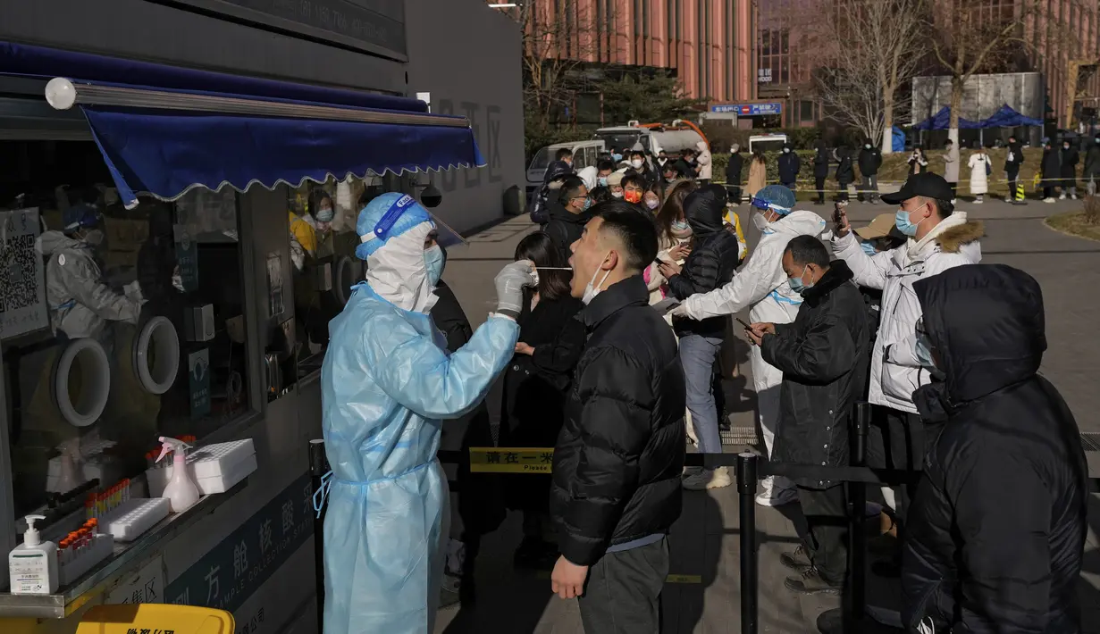 Orang-orang mengantre untuk mendapatkan tes COVID-19 di fasilitas pengujian virus corona seluler di luar gedung perkantoran komersial di Beijing (16/1/2022). Beijing telah melaporkan infeksi omicron lokal pertamanya, beberapa minggu sebelum Olimpiade Musim Dingin akan dimulai. (AP Photo/Andy Wong)