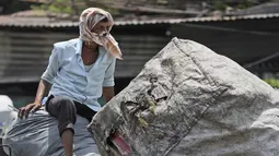 Seorang pria menutupi wajahnya untuk melindungi dirinya dari panas saat bepergian dengan autorickshaw yang membawa sampah di Hyderabad, India, Sabtu, 14 Mei 2022. Suhu di New Delhi mencapai 45 Derajat Celcius. (AP Photo/Mahesh Kumar A.)