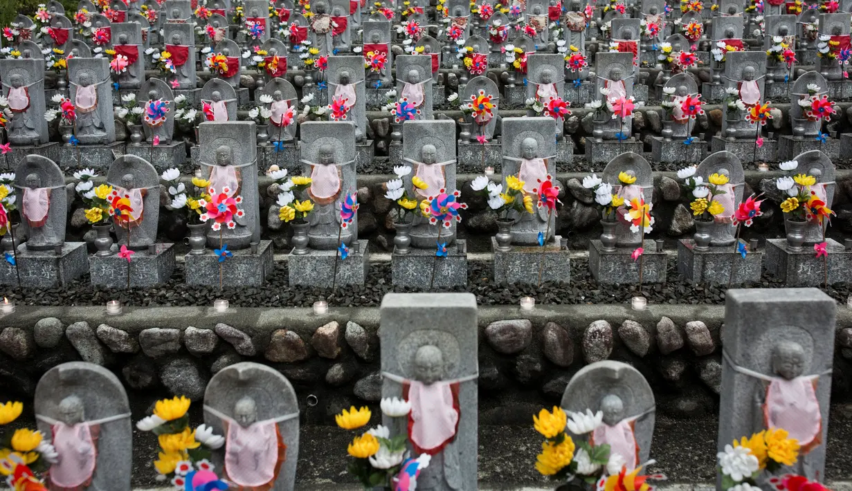 Deretan patung Jizo berdiri di Kuil Buddha Jizoji, Oganomachi, Prefektur Saitama, Jepang, Senin (13/8). Patung Jizo diyakini sebagai pelindung bagi anak-anak yang belum sempat lahir atau telah meninggal dunia. (Behrouz Mehri/AFP)