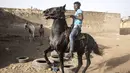 Seorang joki berlatih untuk mengendalikan kudanya di Ouagadougou (1/2/2022). Koboi terkenal memenangkan jutaan Franc Afrika Barat dari balapan dan diam-diam melatih kuda di malam hari untuk melakukan dressage, beberapa bahkan menyebut diri mereka koboi dan berpakaian sesuai. (AFP/John Wessels)