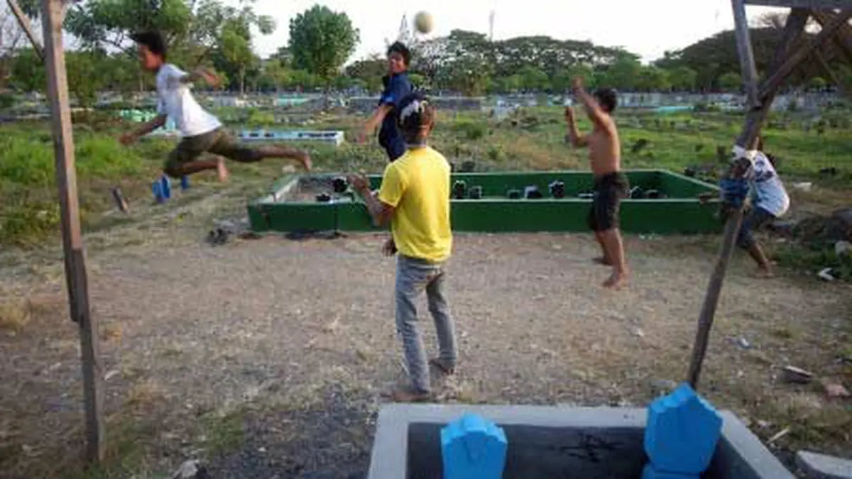 Sejumlah warga bermain sepak bola di Tempat Pemakaman Umum (TPU) Rangkah karena minimnya lahan sarana fasilitas umum untuk arena bermain di Surabaya. (Antara) - Photo Liputan6.com