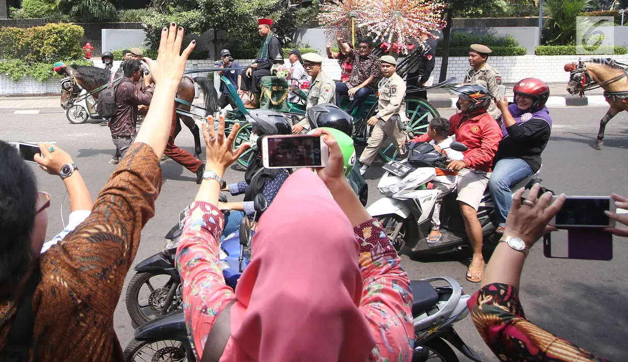 Gubernur DKI Jakarta Djarot Saiful Hidayat bersama istri Happy Farida menaiki delman sambil melambaikan tangan kepada warga dan pegawai Pemprov DKI Jakarta saat perpisahan dirinya di Balaikota DKI Jakarta, Minggu (15/10). (Liputan6.com/Immanuel Antonius)