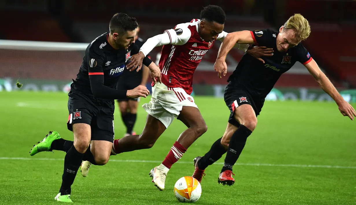 Gelandang Arsenal, Joe Willock, berusaha melewati dua pemain Dundalk pada laga lanjutan Liga Europa 2020/2021 di Emirates Stadium, Jumat (30/10/2020) dini hari WIB. Arsenal menang 3-0 atas Dundalk. (AFP/Glyn Kirk)