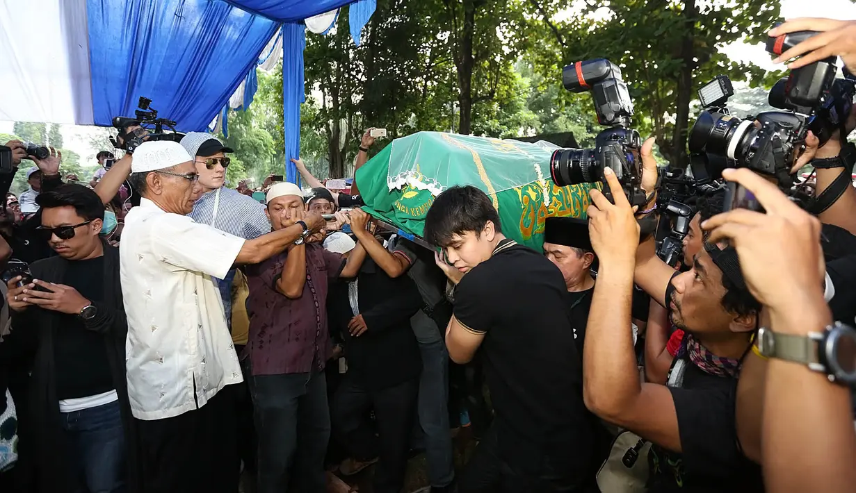 Lantunan doa dan ayat suci Al Quran tak henti mengiringi proses pemakaman Jupe. Suasana pun semakin haru ketika secara perlahan tanah merah itu menutupi jasad Jupe yang tertutup kain dan papan di liang lahat. (Bambang E.Ros/Bintang.com)