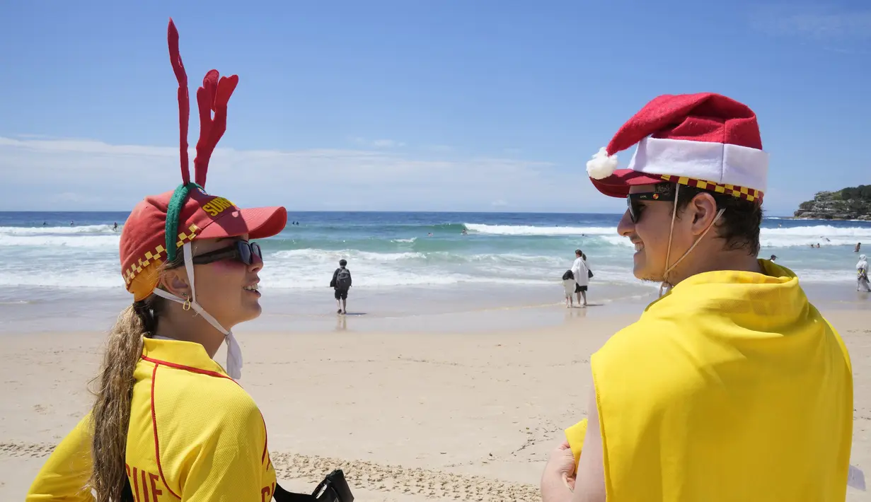 Penyelamat selancar Summer Robinson, kiri, dan Lachlan Sharp mengawasi para wisatawan yang sedang berlibur di Pantai Bondi di Sydney, Senin, 25 Desember 2023. (AP Photo/Rick Rycroft)