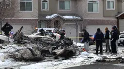 Tim penyelamat melihat puing-puing pesawat pribadi yang jatuh di kawasan perumahan Roy, Utah, Amerika Serikat, Rabu (15/1/2020). Pesawat menabrak atap rumah sebelum akhirnya menghantam tanah dan terbakar. (Steve Griffin/The Deseret News via AP)
