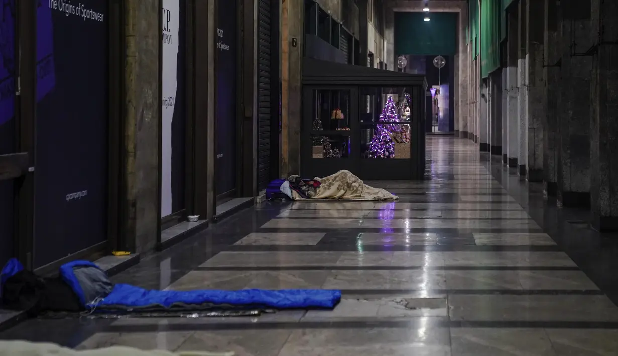 Tunawisma tidur di emperan toko di Milan, Italia, 27 November 2020. Dinas Pertanian di Italia mengatakan bahwa pandemi virus Corona telah menciptakan 300.000 yang disebut "orang miskin baru,” berdasarkan survei dari asosiasi amal yang beroperasi di Lombardy tersebut. (AP Photo/Luca Bruno)