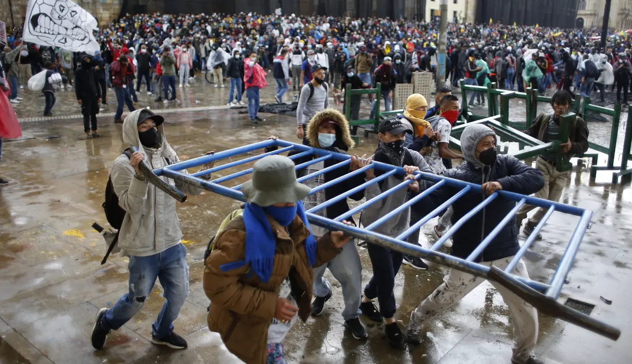 Para pengunjuk rasa membawa pagar untuk membuat barikade selama pemogokan nasional untuk memprotes reformasi pajak yang diusulkan pemerintah, di ibu kota Kolombia, Bogota, pada Rabu (28/4/2021). (AP Photo/Fernando Vergara)