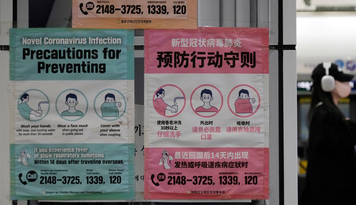 Seorang wanita bermasker melewati poster yang mengingatkan tindakan pencegahan terhadap virus corona COVID-19 di stasiun kereta bawah tanah di Seoul, Korea Selatan, Jumat (10/2/2023). Korea Selatan mengatakan akan menghapus pembatasan masuk yang diberlakukan pada pelancong jangka pendek dari China sejak awal tahun karena para pejabat melihat situasi COVID-19 di negara itu mulai stabil. (AP Photo/Ahn Young-joon)