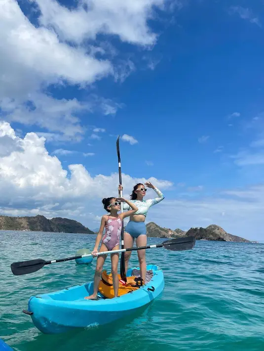 Pose kompak kece Tyna Dwi Jayanti di atas perahu warna biru bersama putrinya, Aluna Mirdad. Tyna mengenakan long sleeve bikini bernuansa biru. Untuk bawahan bikini memiliki model high waist yang memberi kesan sporty. (Instagram/tynadwijayanti)
