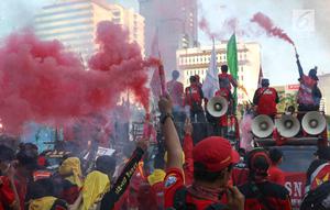 Sejumlah buruh menyalakan bom asap saat menutup aksi Hari Buruh Internasional di Jalan Medan Merdeka Barat, Jakarta, Rabu (5/1/2019). Aksi May Day 2019 di Jakarta ditutup oleh buruh dengan menyalakan kembang api sebagai simbol berjalannya demo dengan damai. (Liputan6.com/Helmi Fithriansyah)