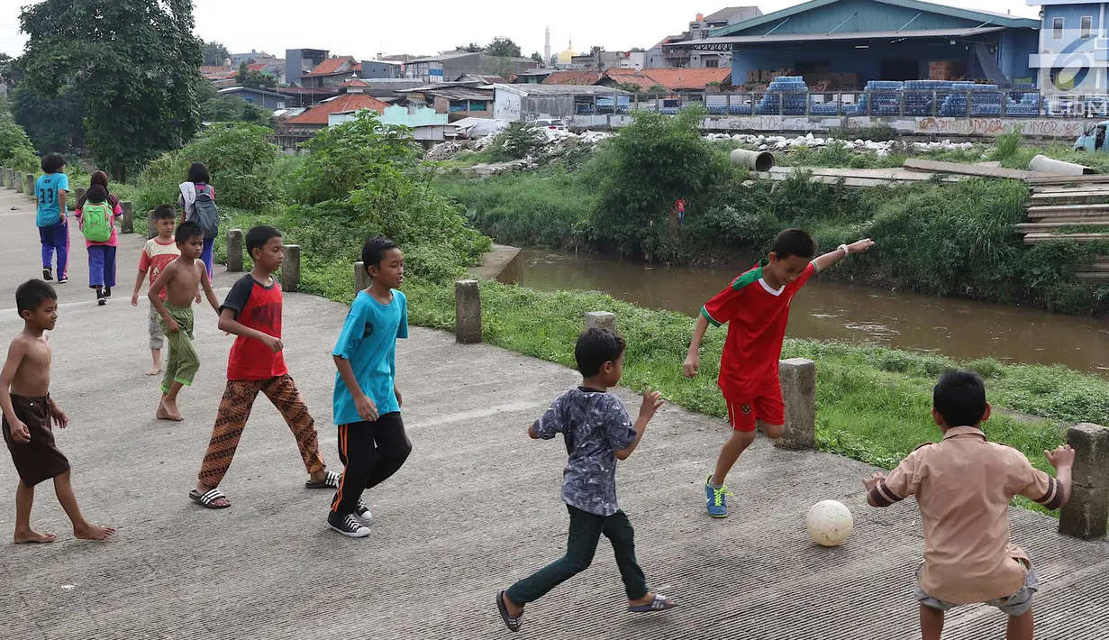 Anak-anak bermain sepak bola di jalur inspeksi Sungai Ciliwung di kawasan Rawajati, Jakarta, Rabu (23/1). Keterbatasan lahan tidak menyurutkan semangat mereka untuk bermain sepak bola meski di tempat seadanya. (Liputan6.com/Immanuel Antonius)