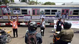 Komunitas Indonesian Railway Preservation Society melakukan aksi Kampanye Keamanan Perlintasan Sebidang Kereta Api di Menteng, Jakarta, Kamis (15/10). Kampanye itu guna menyadarkan bahaya menerobos perlintasan kereta api. (Liputan6.com/Immanuel Antonius)