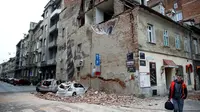 Seorang pria berjalan melewati sebuah bangunan yang rusak dan mobil-mobil hancur oleh puing-puing setelah gempa di jalan-jalan pusat kota Zagreb (22/3/2020).  Gempa magnitudo 5,3 ini tercatat sebagai yang terbesar, yang mempengaruhi Kroasia dalam 140 tahun. (AFP/Damir Sencar)