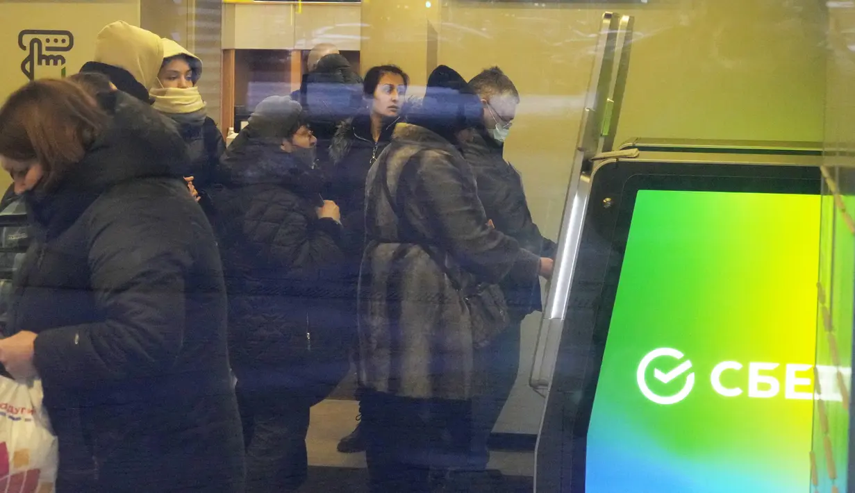 Orang-orang mengantre untuk menarik uang dari ATM di Sberbank di St. Petersburg, Rusia, 25 Februari 2022. Warga Rusia berbondong-bondong ke bank dan ATM tak lama setelah Rusia melancarkan serangan ke Ukraina dan Barat mengumumkan sanksi yang melumpuhkan ekonomi. (AP Photo/Dmitri Lovetsky)