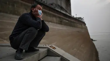 Seorang pria yang memakai masker wajah melihat ke Sungai Yangtze di Wuhan (20/11/2020). Dari total 50.340 kasus yang positif di Wuhan, 3.869 orang telah meninggal dunia akibat Covid-19 dan yang sembuh 46.471 orang. (AFP/Hector Retamal)