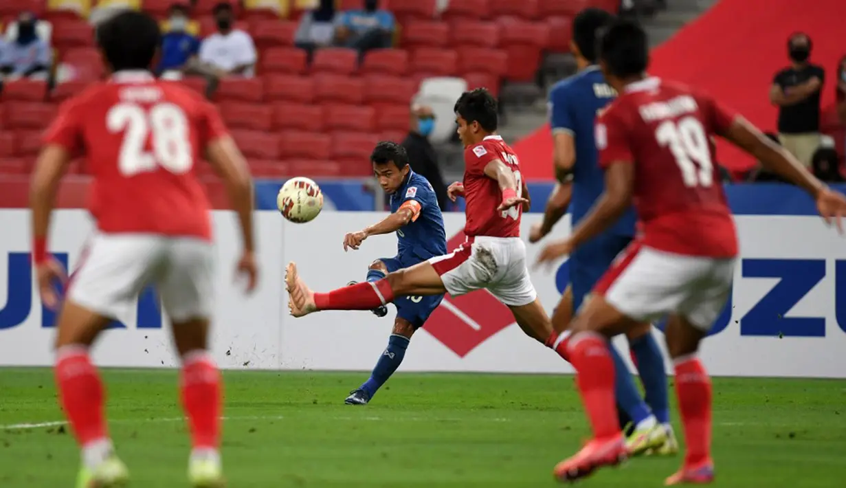Pemain Thailand Chanathip Songkrasin (kedua kiri) menendang bola melewati pemain Indonesia Rachmat Irianto (tengah) pada pertandingan sepak bola leg kedua final Piala AFF 2020 di National Stadium, Singapura, Sabtu (1/1/2022). Pertandingan berakhir dengan skor 2-2. (Roslan RAHMAN/AFP)